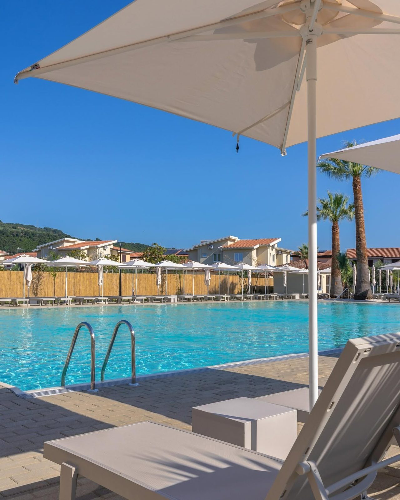 Lettini e grande ombrellone a bordo piscina